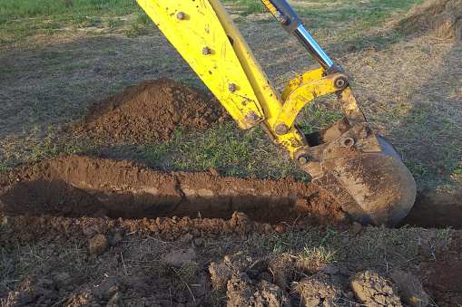 A work excavator digs a trench in a country house 2018