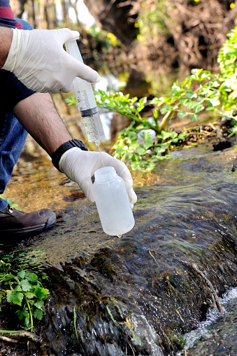 Biologist that collects samples in a water course for the analysis of its pollution and for the study of its characteristics.